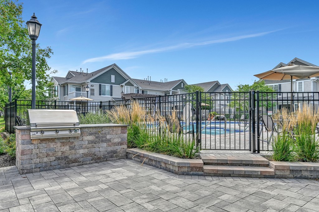 outdoor patio grilling station next to a fenced-in swimming pool