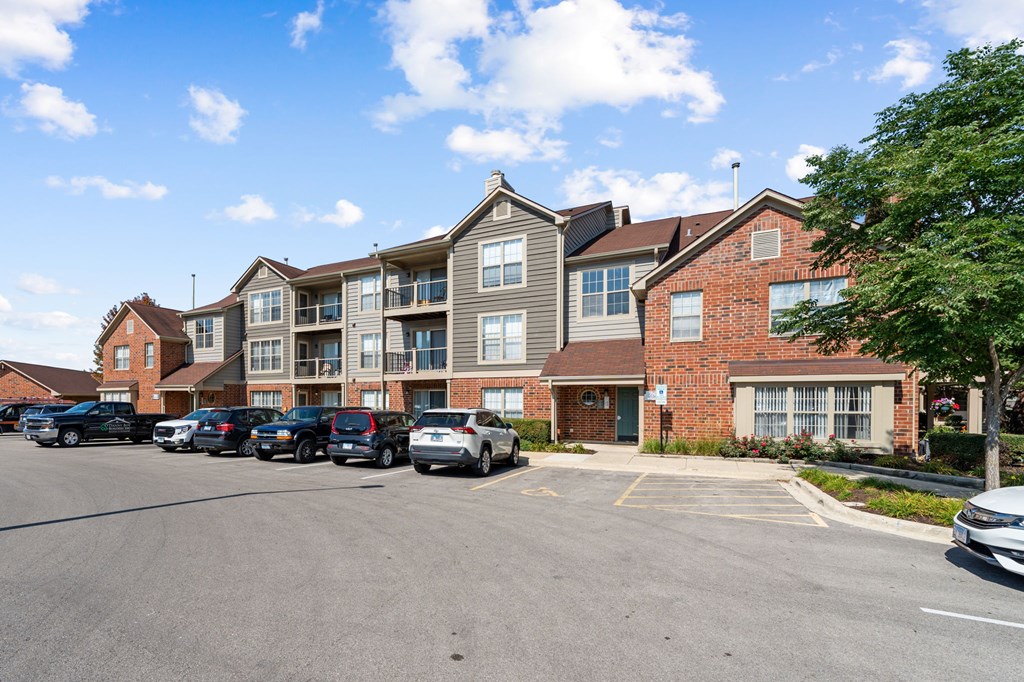 A parking lot in front of a multi-story apartment building.