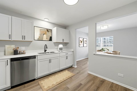 A kitchen with white cabinets and a wooden floor.