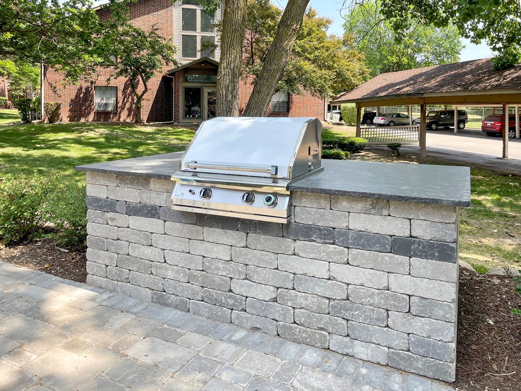 an outdoor kitchen with a grill on top of a brick wall