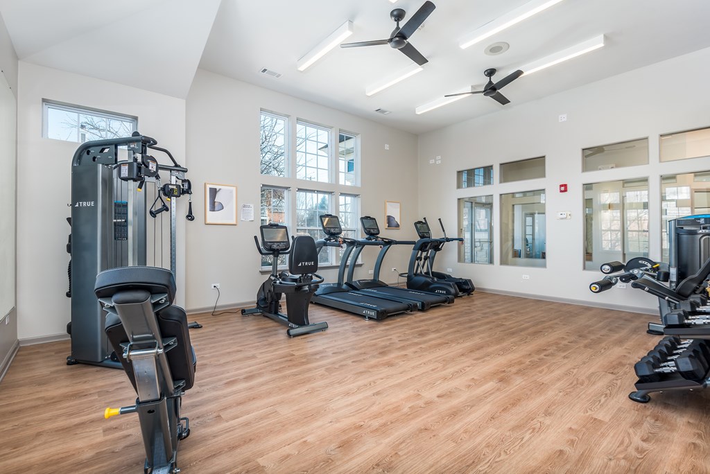 A spacious gym with a variety of equipment including treadmills, elliptical machines, and a weight machine.