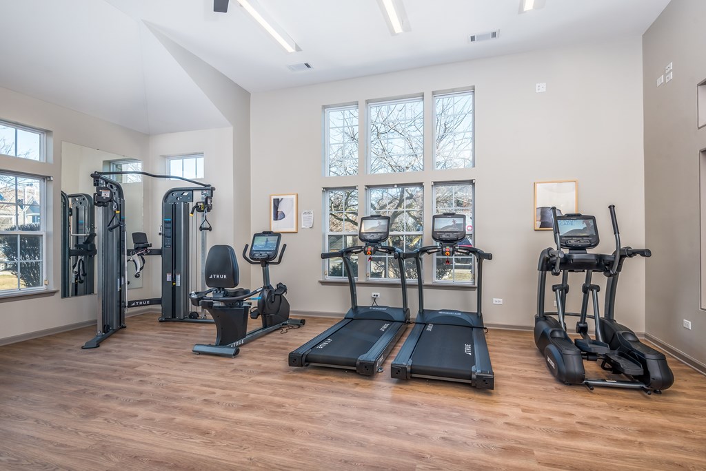 A spacious gym with treadmills, elliptical machines, and a weight machine.