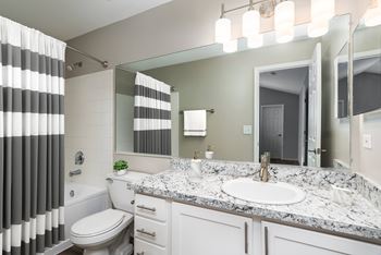 A bathroom with a marble countertop and a striped shower curtain.