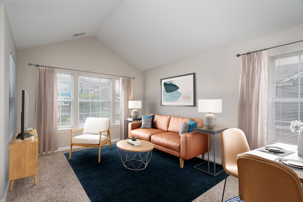 A living room with a brown leather couch, a white chair, and a wooden entertainment center.