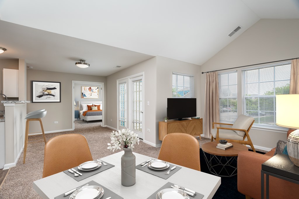 A modern dining room with a table set for two and a television in the corner.