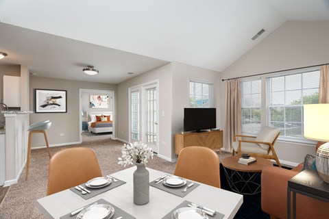 A modern dining room with a table set for two and a television in the corner.