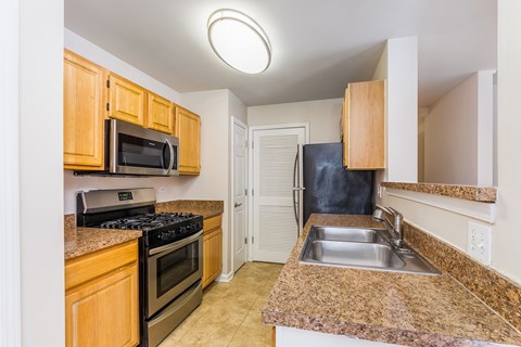 A kitchen with a black fridge and a stove top oven.