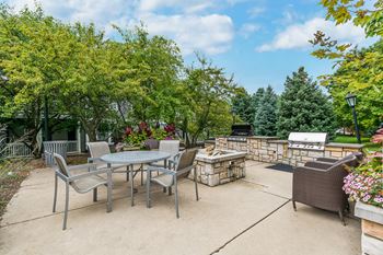 A patio with a table and chairs surrounded by trees.