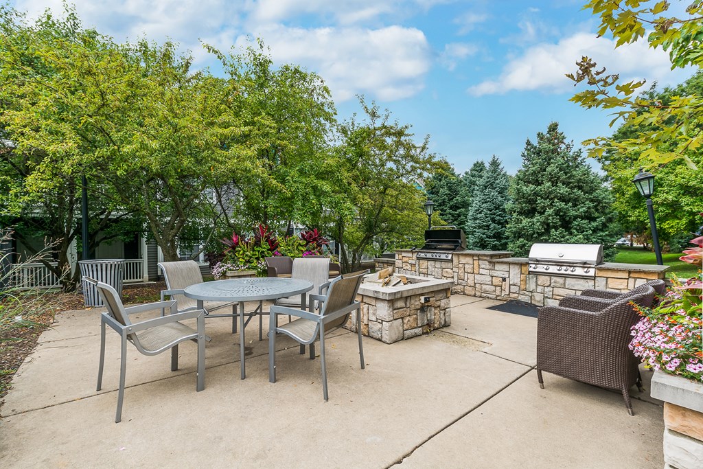 A patio with a table and chairs surrounded by trees.