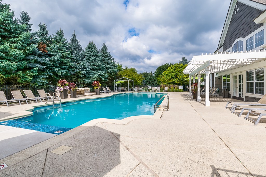 A large outdoor swimming pool surrounded by trees and lounge chairs.