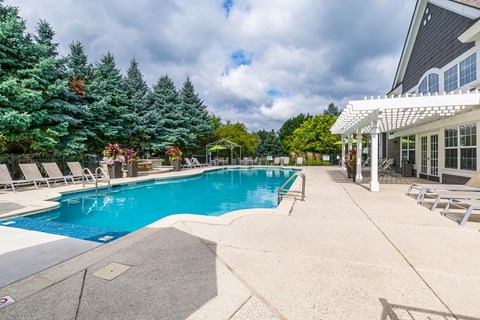 A large outdoor swimming pool surrounded by trees and lounge chairs.