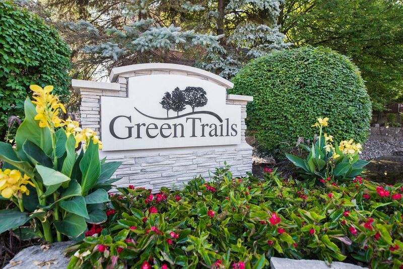 a sign for green trails with plants and flowers