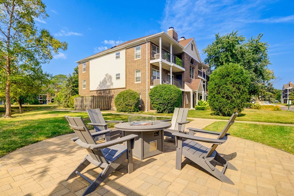 A patio with a table and chairs is in front of a brick apartment building.