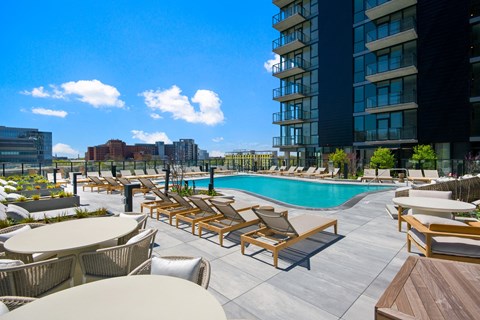 a swimming pool with chaise lounge chairs and tables next to a tall building