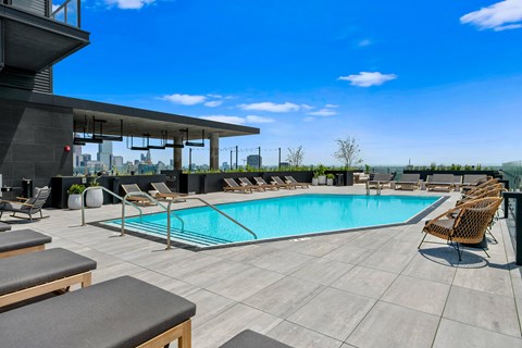A pool area with lounge chairs and a view of the city.