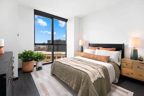 A bedroom with a large bed and a view of the city through the window.