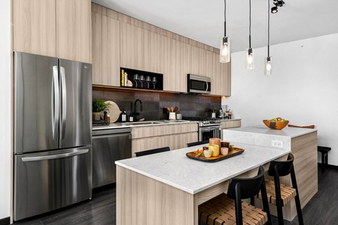 A modern kitchen with a stainless steel refrigerator and a marble countertop.