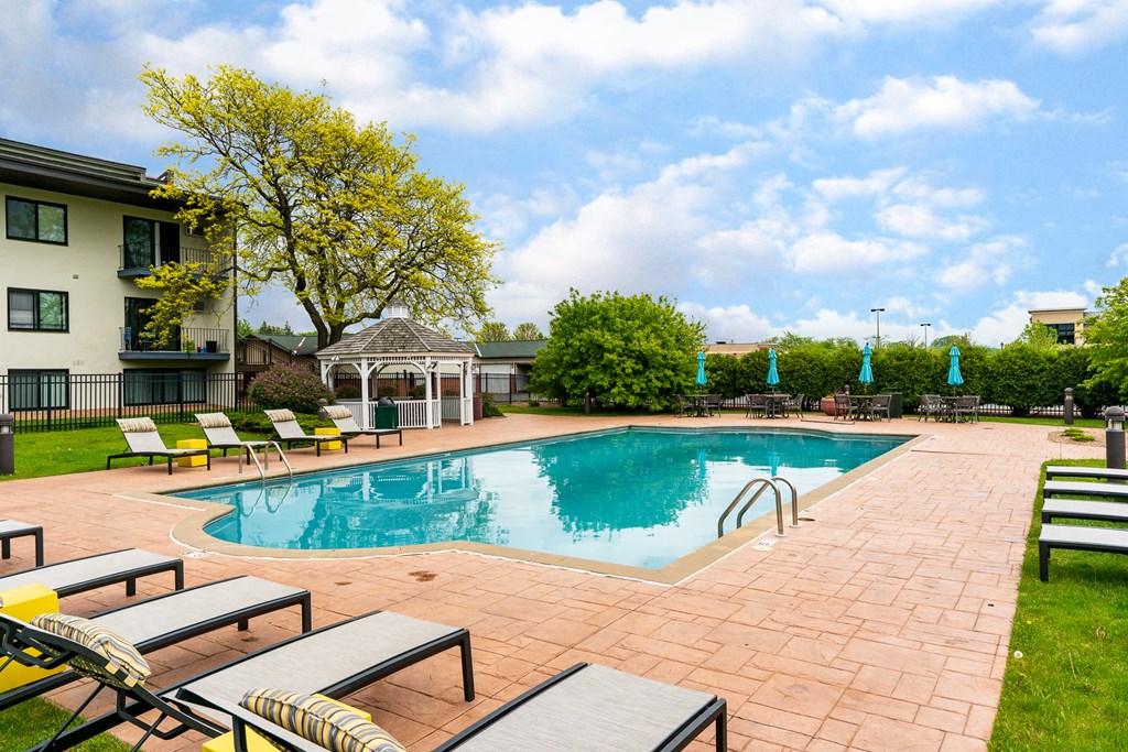 a swimming pool with lounge chairs around it in front of a building