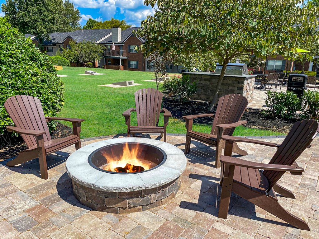 a fire pit with chairs around it on a brick patio
