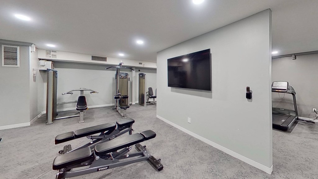 a gym with exercise machines and a tv on the wall