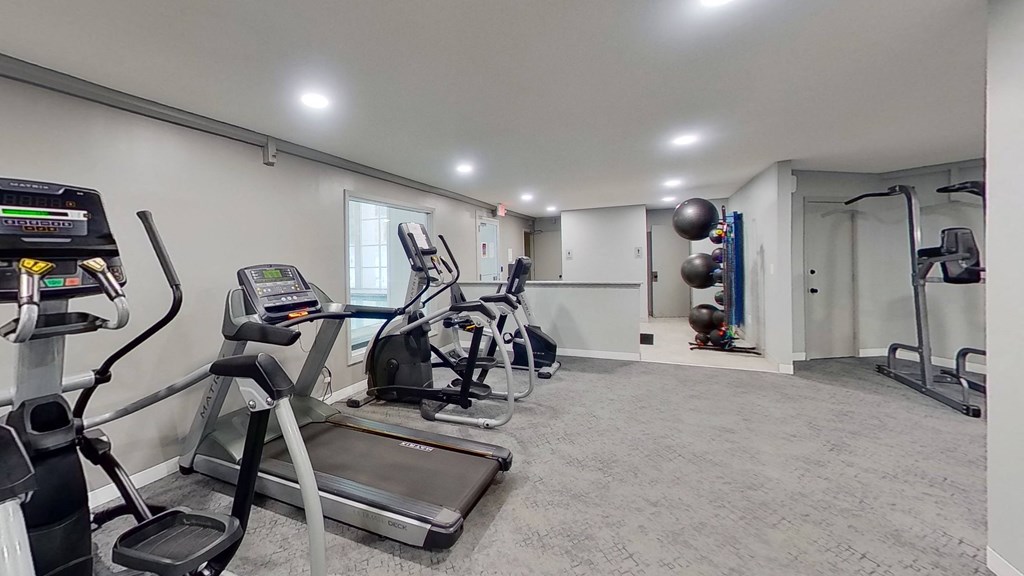 a gym with exercise machines and weights in a room with a window