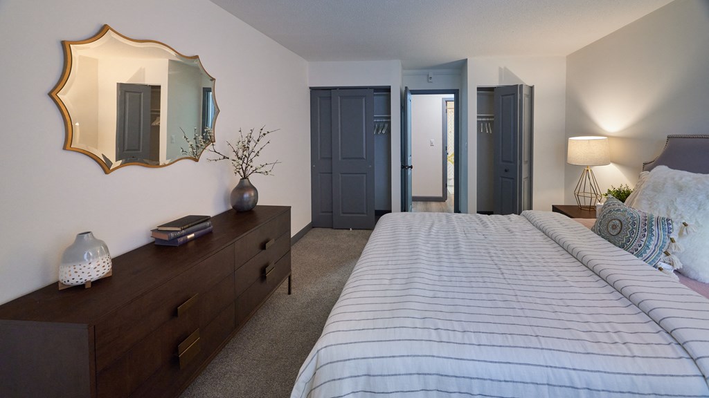 a bedroom with a bed and a dresser with a mirror