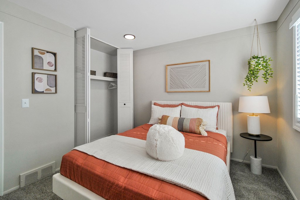 a bedroom with an orange and white bed and a closet