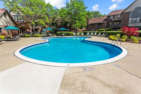 A round blue swimming pool surrounded by a concrete patio and a white border.