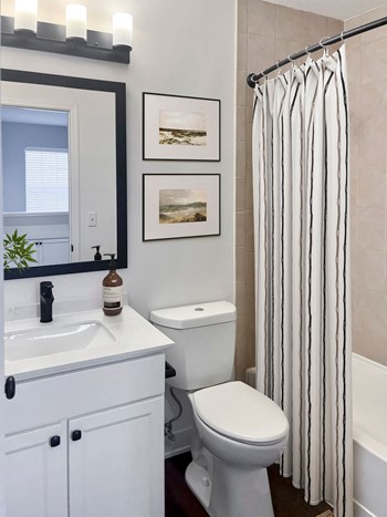 a small bathroom with a white sink and toilet and a white bathtub with a shower curtain - Photo Gallery 27