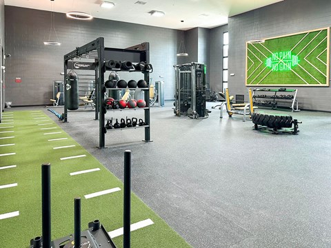 a gym with weights and a scoreboard on the wall
