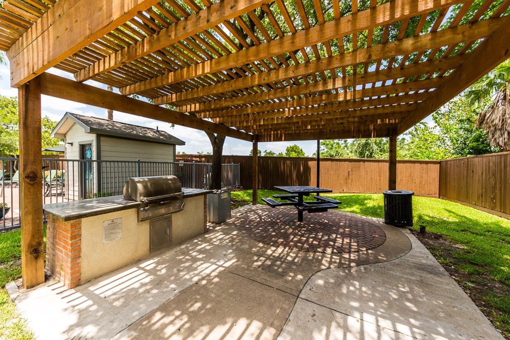 a covered patio with a grill and a picnic table