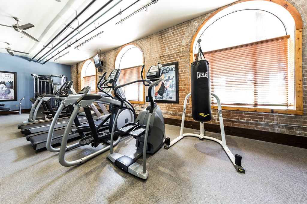 a gym with cardio equipment and weights in a building with brick walls