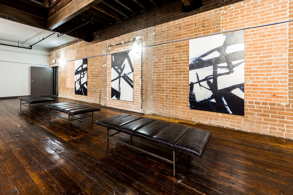 a room with benches and paintings on a brick wall