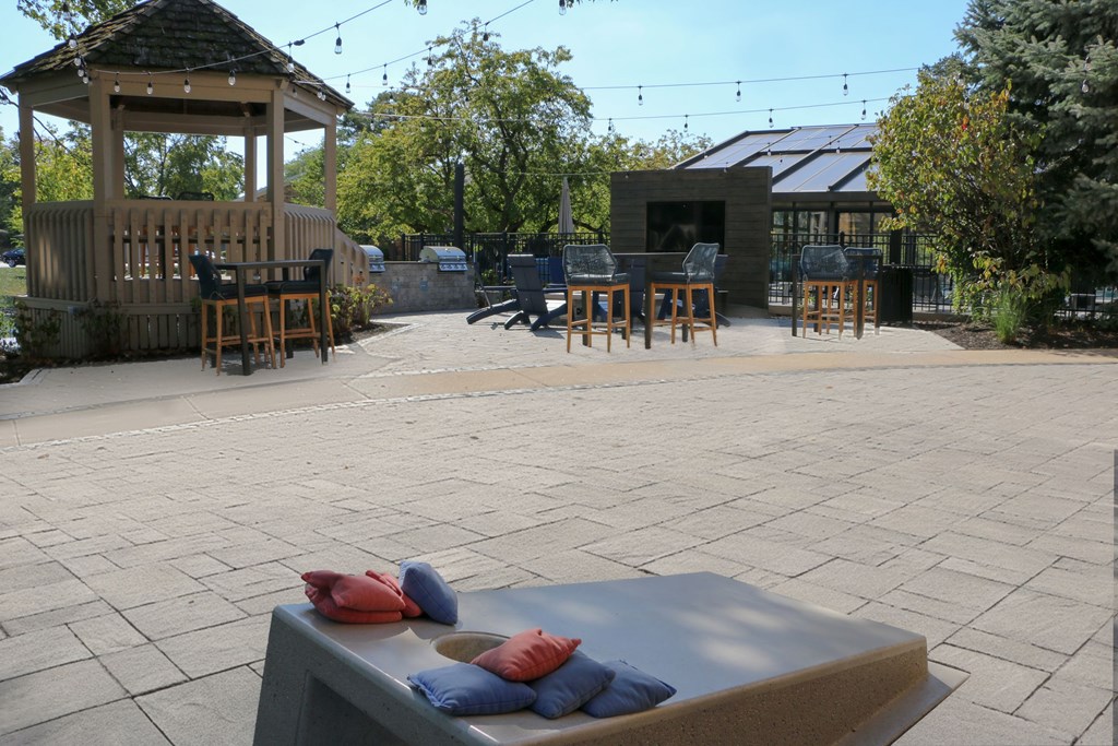 A gazebo is surrounded by a patio with a table and chairs.