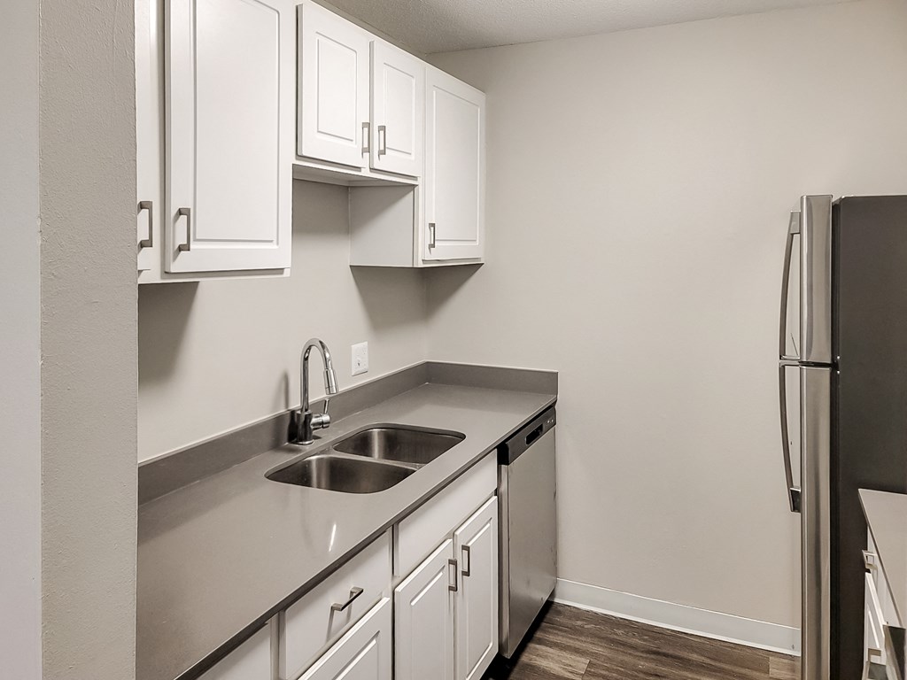 an empty kitchen with white cabinets and a stainless steel sink