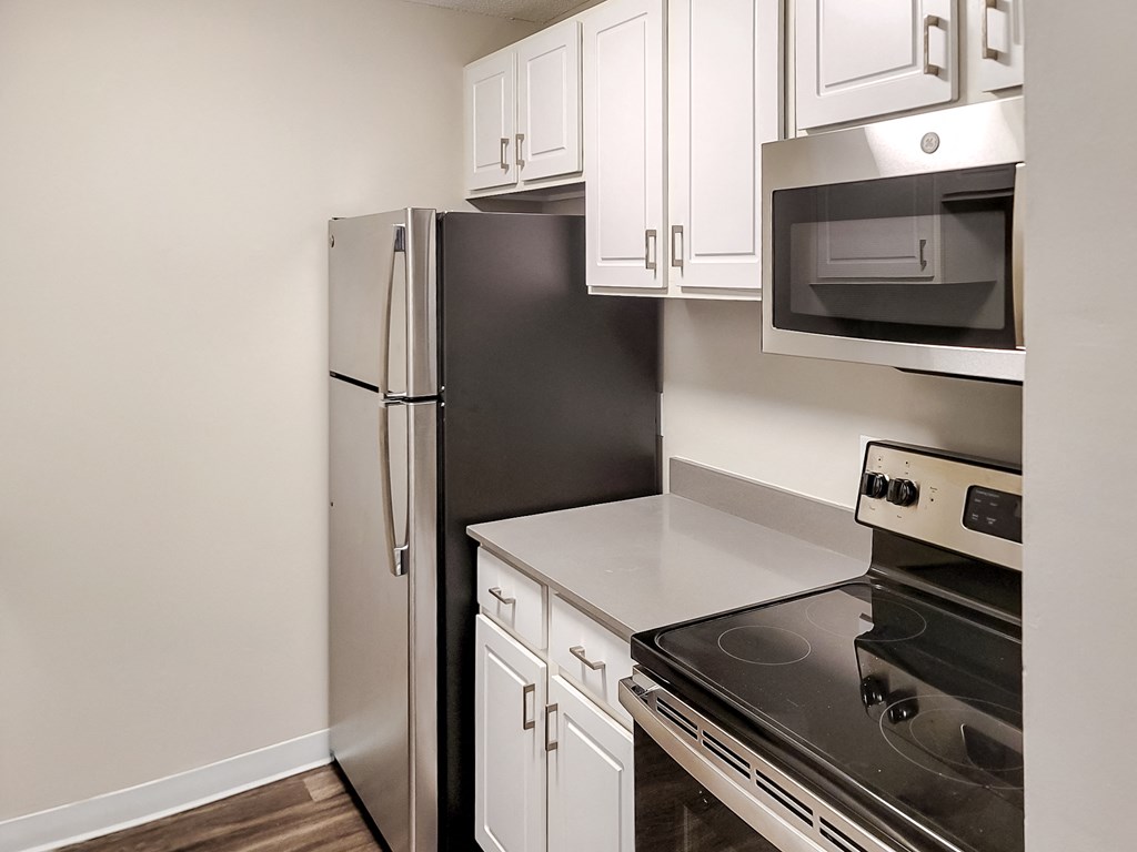 a kitchen with white cabinets and black appliances and a refrigerator