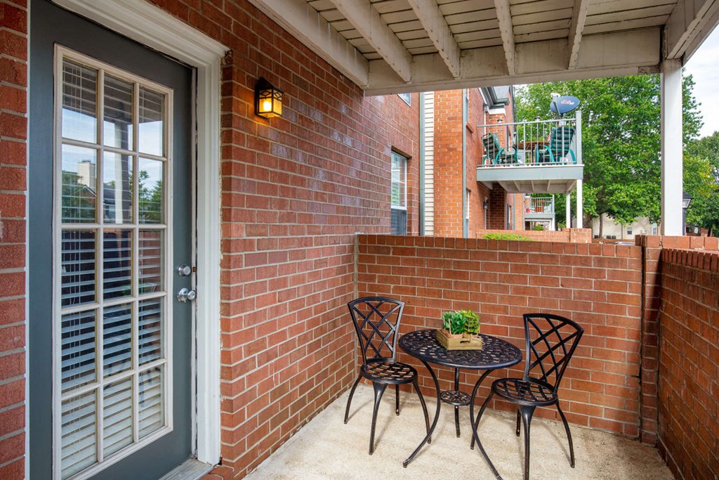 a patio with a table and chairs in front of a brick wall