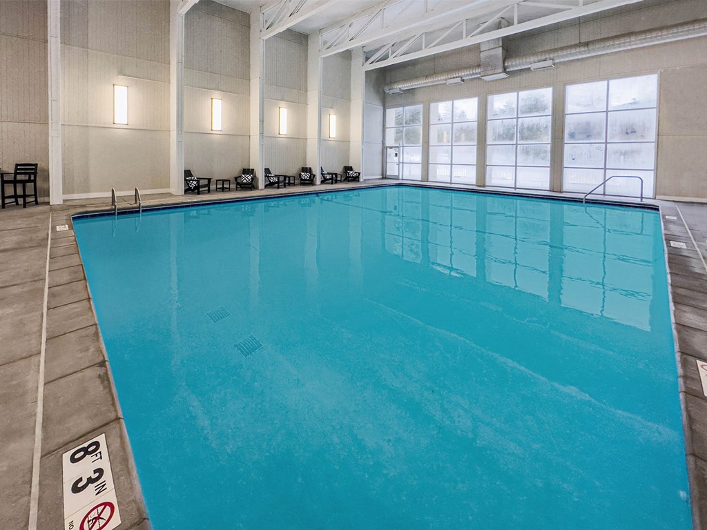 a large pool in a building with chairs around it