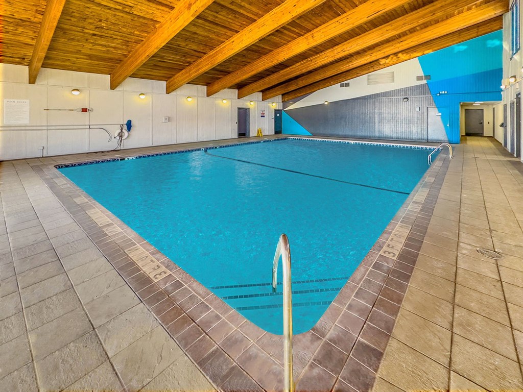 a swimming pool in a building with a wooden ceiling and tile floors