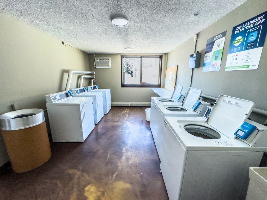 an empty laundry room with washes and dryers in it