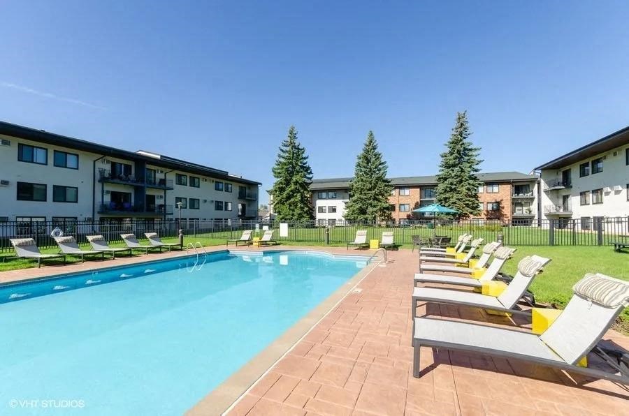 a swimming pool with lounge chairs next to an apartment building
