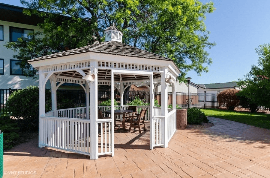 a gazebo with a table and chairs in a courtyard