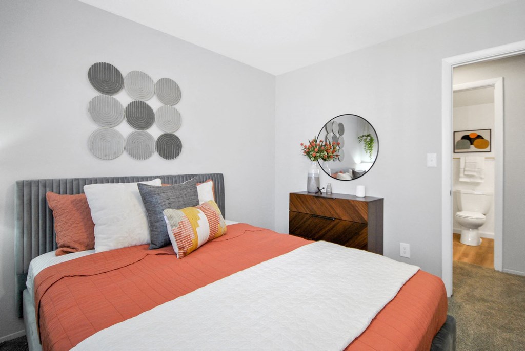 carpeted bedroom with a bright bed and wall art