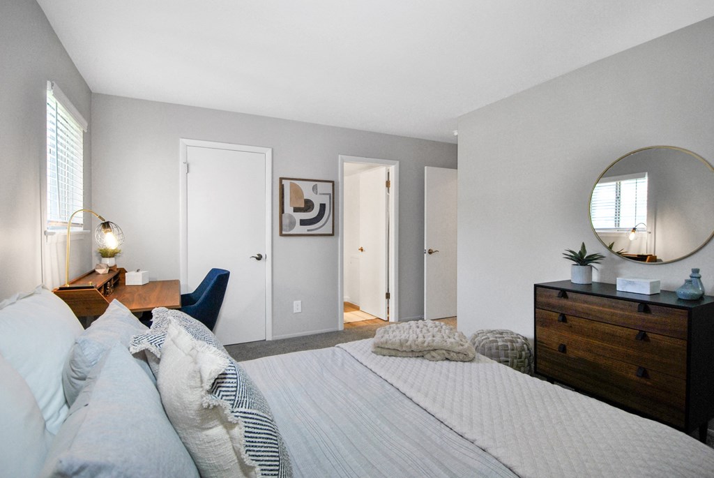 apartment bedroom with a bed, desk, and dresser