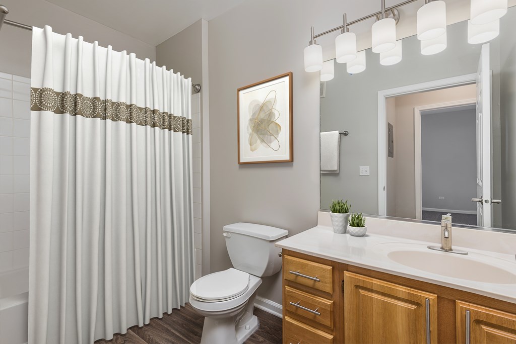 A white toilet sits in a bathroom with a white sink and a mirror.