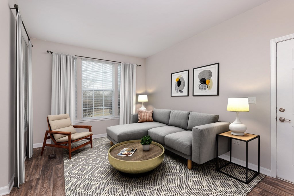 A living room with a grey couch, a wooden chair, a coffee table, and two lamps.