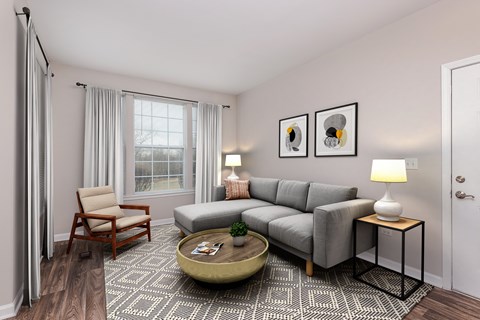 A living room with a grey couch, a wooden chair, a coffee table, and two lamps.