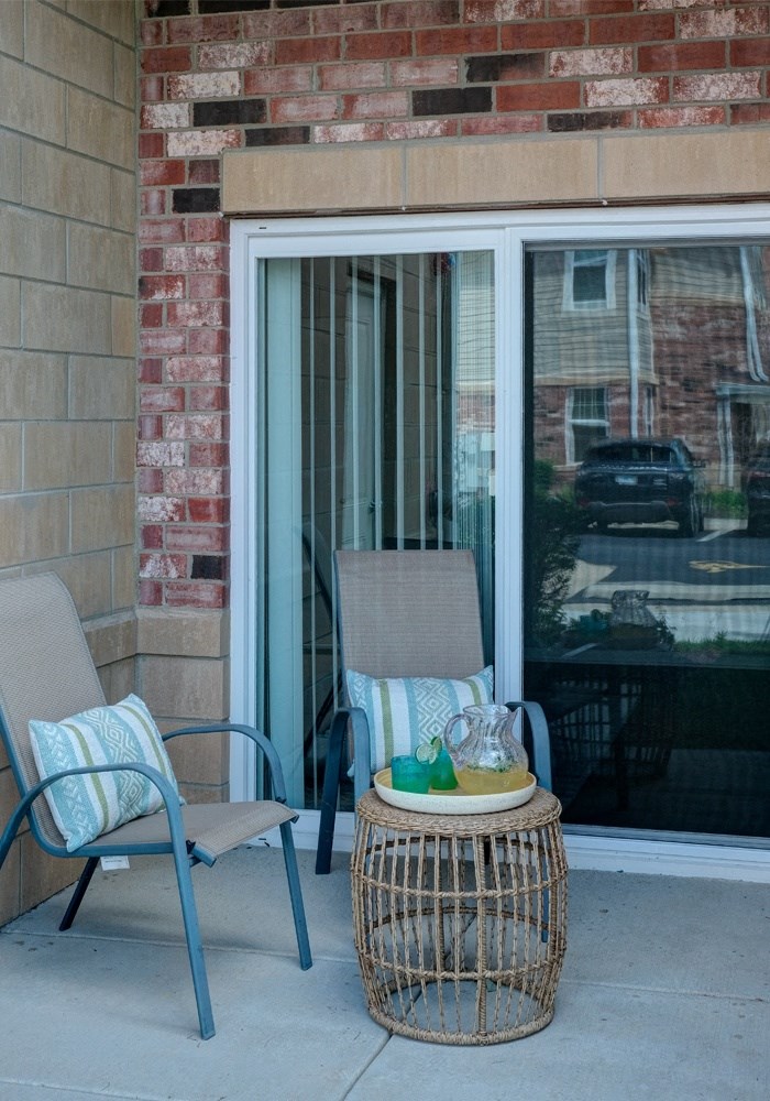 a porch with two chairs and a table with items on it