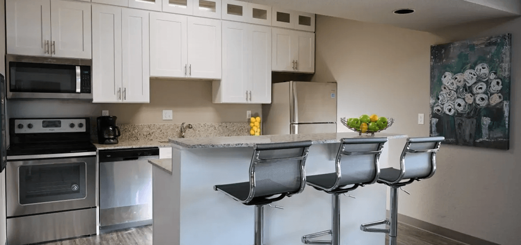 a kitchen with white cabinets and a counter with chairs