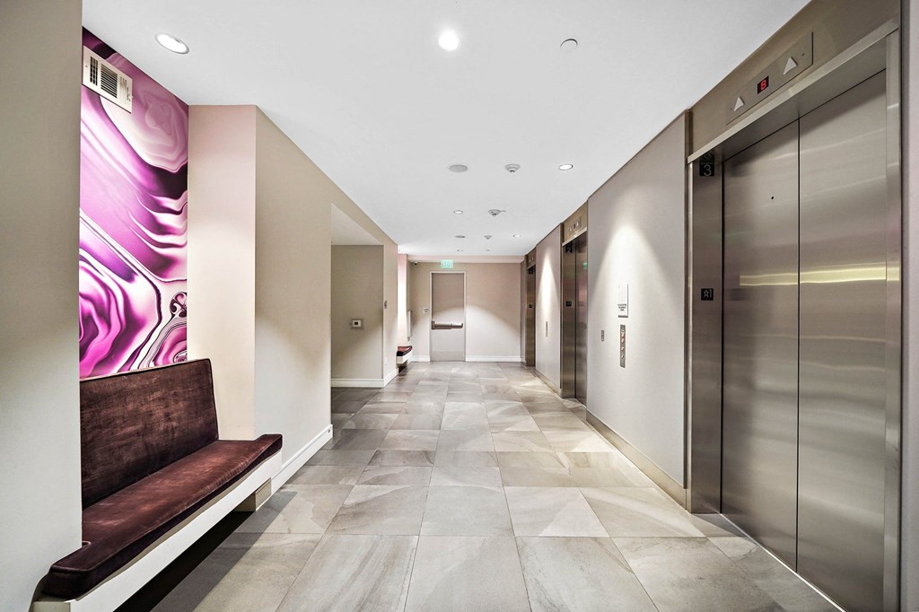 a hallway with elevators and a bench in a lobby